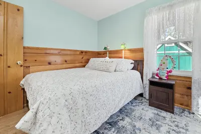 a bedroom with a white bed and a window at Oak Nesting - Great chalet style cabin at the end of the street with rustic stone gas log fireplace! in Big Bear Lake