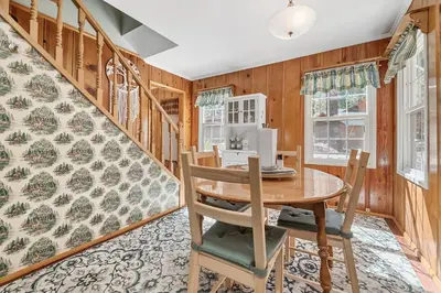 a dining room with a table and chairs and wooden walls at Oak Nesting - Great chalet style cabin at the end of the street with rustic stone gas log fireplace! in Big Bear Lake
