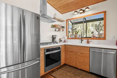 a kitchen with a stainless steel refrigerator and a window at Nightcap Lodge- HOT TUB WITH BREATHTAKING MOUNTAIN VIEWS! in Fawnskin