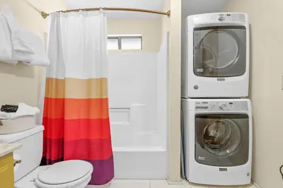 a bathroom with a toilet and a washer and dryer at Nightcap Lodge- HOT TUB WITH BREATHTAKING MOUNTAIN VIEWS! in Fawnskin