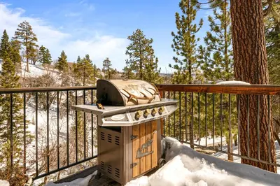 a grill sitting on a deck in the snow at Nightcap Lodge- HOT TUB WITH BREATHTAKING MOUNTAIN VIEWS! in Fawnskin