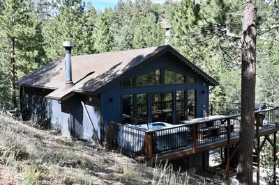 a small house with a porch and a deck at Nightcap Lodge- HOT TUB WITH BREATHTAKING MOUNTAIN VIEWS! in Fawnskin