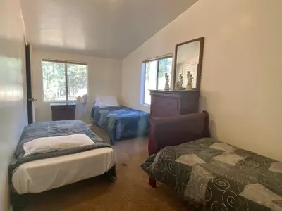 a bedroom with two beds and a chair and a mirror at Mountain Fever - Offers a Foosball Table and Barbecue Grill and a large back deck! in Big Bear Lake