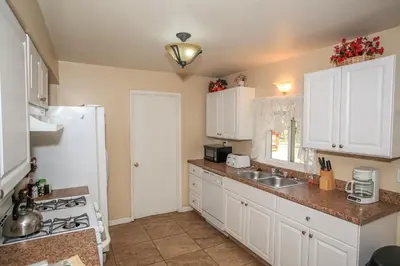 a kitchen with white cabinets and a white refrigerator at Mountain Fever - Offers a Foosball Table and Barbecue Grill and a large back deck! in Big Bear Lake