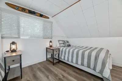 a bedroom with a bed and a surfboard on the wall at Boulder Bay Bungalow - Updated mountain retreat with hot tub, game table, and sauna! in Big Bear Lake