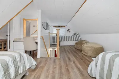 a attic bedroom with two beds and a desk at Boulder Bay Bungalow - Updated mountain retreat with hot tub, game table, and sauna! in Big Bear Lake