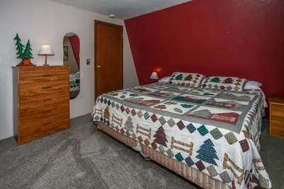 a bedroom with a bed and a dresser with a christmas quilt at Bear 'n Tree - Cozy cabin near the Village in Big Bear Lake