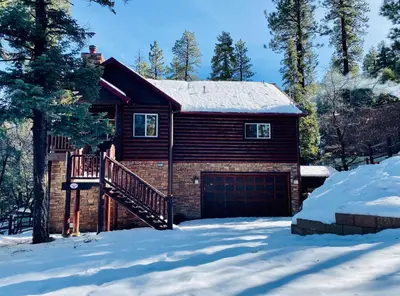 a house with a garage in the snow at Bearfoot Bungalow - Premium and spacious home close to the National Forest and The Village! in Big Bear Lake