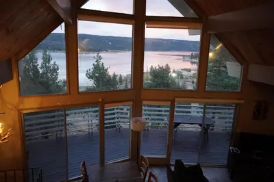 a room with a large window with a view of a lake at Best View - Spacious home with game room, and 180 degree panoramic view of Big Bear Lake! in Fawnskin