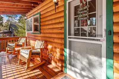 a porch with chairs and a sign on a house at Blue Jay Chalet - Classic mountain cabin in one of Big Bear's quietest neighborhoods! in Big Bear Lake
