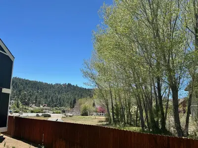 a fence in front of a yard with trees at Boulder Bay Chalet Condo - Mountain charm condo with lake view and WIFI! in Big Bear Lake