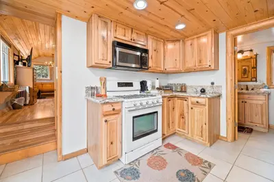 a kitchen with wooden cabinets and a stove at Boulder Bear - Modern mountain home in a desirable area of Big Bear with peek-a-boo lake views in Big Bear Lake