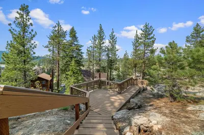 a wooden boardwalk leading to a cabin in the woods at Boulder Bear - Modern mountain home in a desirable area of Big Bear with peek-a-boo lake views in Big Bear Lake