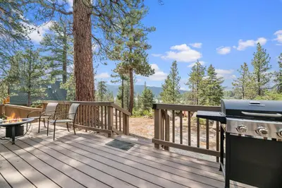 a deck with a grill and a table and chairs at Boulder Bear - Modern mountain home in a desirable area of Big Bear with peek-a-boo lake views in Big Bear Lake
