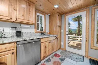 a kitchen with a door leading to a deck at Boulder Bear - Modern mountain home in a desirable area of Big Bear with peek-a-boo lake views in Big Bear Lake