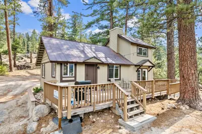 a tiny house in the woods with a large deck at Boulder Bear - Modern mountain home in a desirable area of Big Bear with peek-a-boo lake views in Big Bear Lake