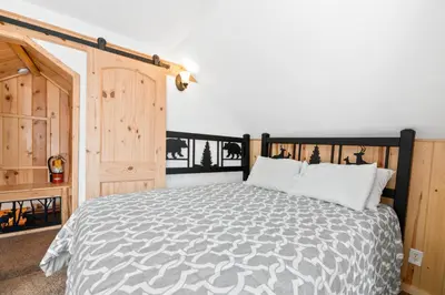 a bedroom with a bed with a black and white comforter at Boulder Bear - Modern mountain home in a desirable area of Big Bear with peek-a-boo lake views in Big Bear Lake