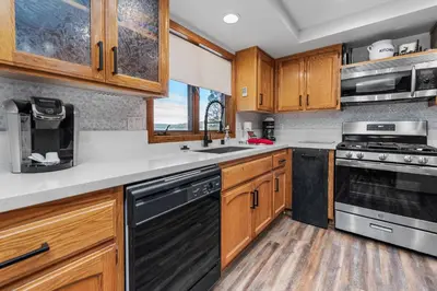 a kitchen with wooden cabinets and black appliances at Grand Lakefront Escape - Gorgeous Lakefront home with Hot Tub and Game Room! in Big Bear Lake
