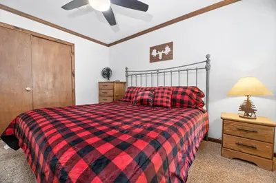 a bedroom with a bed with a red and black plaid blanket at Grand Lakefront Escape - Gorgeous Lakefront home with Hot Tub and Game Room! in Big Bear Lake