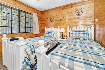two beds in a room with wooden walls and windows at Hidden Spot - Desirable Fox Farm area of Big Bear in Big Bear Lake