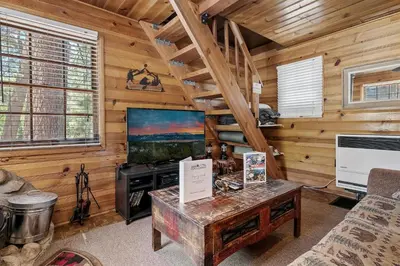 a living room with a large screen tv in a log cabin at Highland Hideaway - Walk to lake and village! in Big Bear Lake