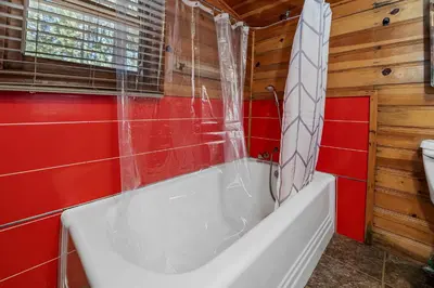 a white bath tub in a bathroom with red tiles at Highland Hideaway - Walk to lake and village! in Big Bear Lake