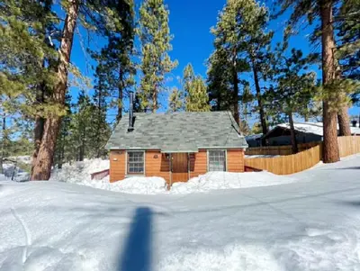a house in the snow with a shadow in the foreground at Highland Hideaway - Walk to lake and village! in Big Bear Lake