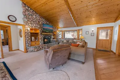 a living room with a couch and a stone fireplace at Kubo Del Sol - DREAM LOCATION WITH HOT TUB! Beautiful, light and bright log cabin! in Big Bear Lake