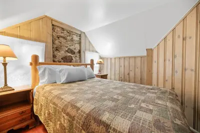 a bedroom with a bed and a stone wall at Lake Cottage - Vintage Big Bear Cabin close to The Village and Lake in Big Bear Lake