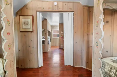 a hallway with wooden walls and a room with two beds at Lake Cottage - Vintage Big Bear Cabin close to The Village and Lake in Big Bear Lake