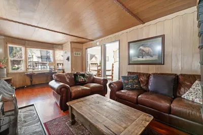 a living room with leather furniture and a table at Lake Cottage - Vintage Big Bear Cabin close to The Village and Lake in Big Bear Lake