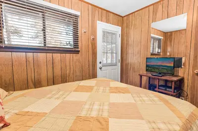 a bedroom with a large bed and a television at Lakefront Retreat - Lakefront cabin near Holloways Marina in Big Bear Lake