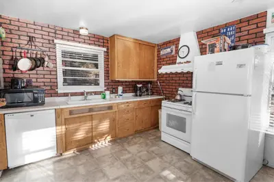 a kitchen with white appliances and a brick wall at Lakefront Retreat - Lakefront cabin near Holloways Marina in Big Bear Lake