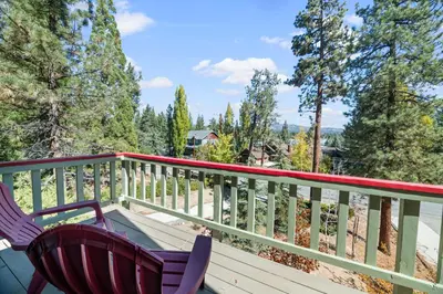 a table and two chairs on a deck with trees at Lakeview Haven - Large cabin with game room close to the lake! in Big Bear Lake