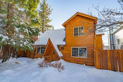 a log cabin in the snow with a fence at Mallard Landing - Steps from the marina and minutes from the Village in Big Bear Lake