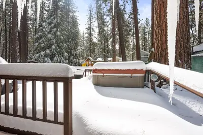 a snow covered yard with a fence and trees at Nunu's Cabin - Beautiful cabin, close to ski resorts and town, Hot Tub and Board Games! in Big Bear Lake