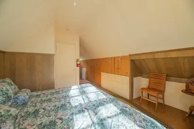 a bedroom with a large bed and a chair at Rustic Pine - Rustic true log cabin with plenty of charm, Close to everything! in Big Bear Lake