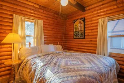 a bedroom with a bed in a log cabin at Rustic Pine - Rustic true log cabin with plenty of charm, Close to everything! in Big Bear Lake