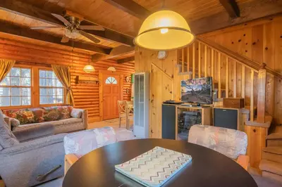 a living room with a table and a couch at Rustic Pine - Rustic true log cabin with plenty of charm, Close to everything! in Big Bear Lake