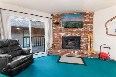 a living room with a couch and a brick fireplace at Snow Summit Getaway - Walk to Snow Summit Ski Resort in Big Bear Lake