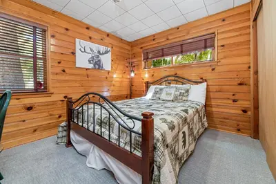 a bedroom with a bed in a room with wooden walls at Stillwater Cove Lakefront - Breathtaking views, charming vintage cabin, woodsy interior! Boat Dock! in Big Bear Lake