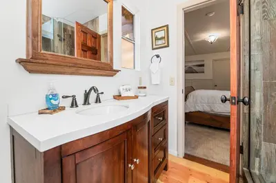 a bathroom with a sink and a bedroom at Stillwater Cove Lakefront - Breathtaking views, charming vintage cabin, woodsy interior! Boat Dock! in Big Bear Lake