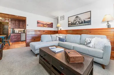 a living room with a couch and a coffee table at Stillwater Cove Lakefront - Breathtaking views, charming vintage cabin, woodsy interior! Boat Dock! in Big Bear Lake