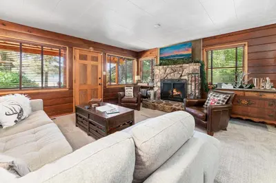 a living room with a couch and a fireplace at Stillwater Cove Lakefront - Breathtaking views, charming vintage cabin, woodsy interior! Boat Dock! in Big Bear Lake