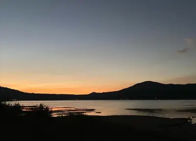 a sunset over a lake with mountains in the background at Summit Condo - Luxury condo, walk to the slopes! in Big Bear Lake