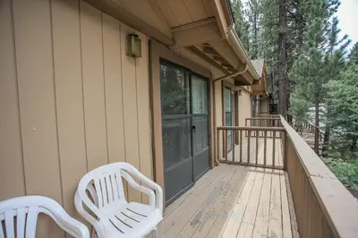 two white chairs sitting on the front porch of a house at Summit Getaway Condo - Affordable and ideally located, Wood burning fireplace! Walk to Ski Resort in Big Bear Lake