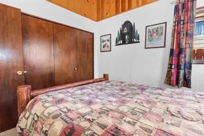 a bedroom with a bed and a wooden cabinet at The Cuddle Inn - True feeling of a great cabin! Beautiful and homey! Walking distance to the lake! in Big Bear Lake