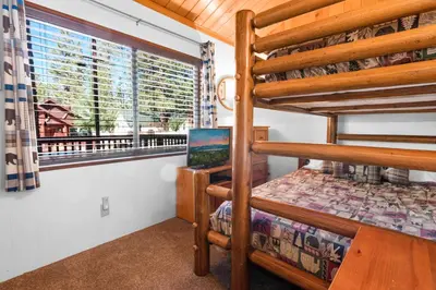 a bedroom with two bunk beds and a window at The Cuddle Inn - True feeling of a great cabin! Beautiful and homey! Walking distance to the lake! in Big Bear Lake