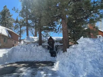 a pile of snow in front of a house at The Cuddle Inn - True feeling of a great cabin! Beautiful and homey! Walking distance to the lake! in Big Bear Lake