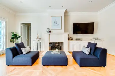 a living room with two blue chairs and a fireplace at Le Jardin in Los Angeles